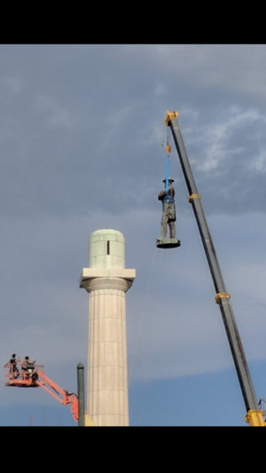 statue being taken off a pedestal with a crane